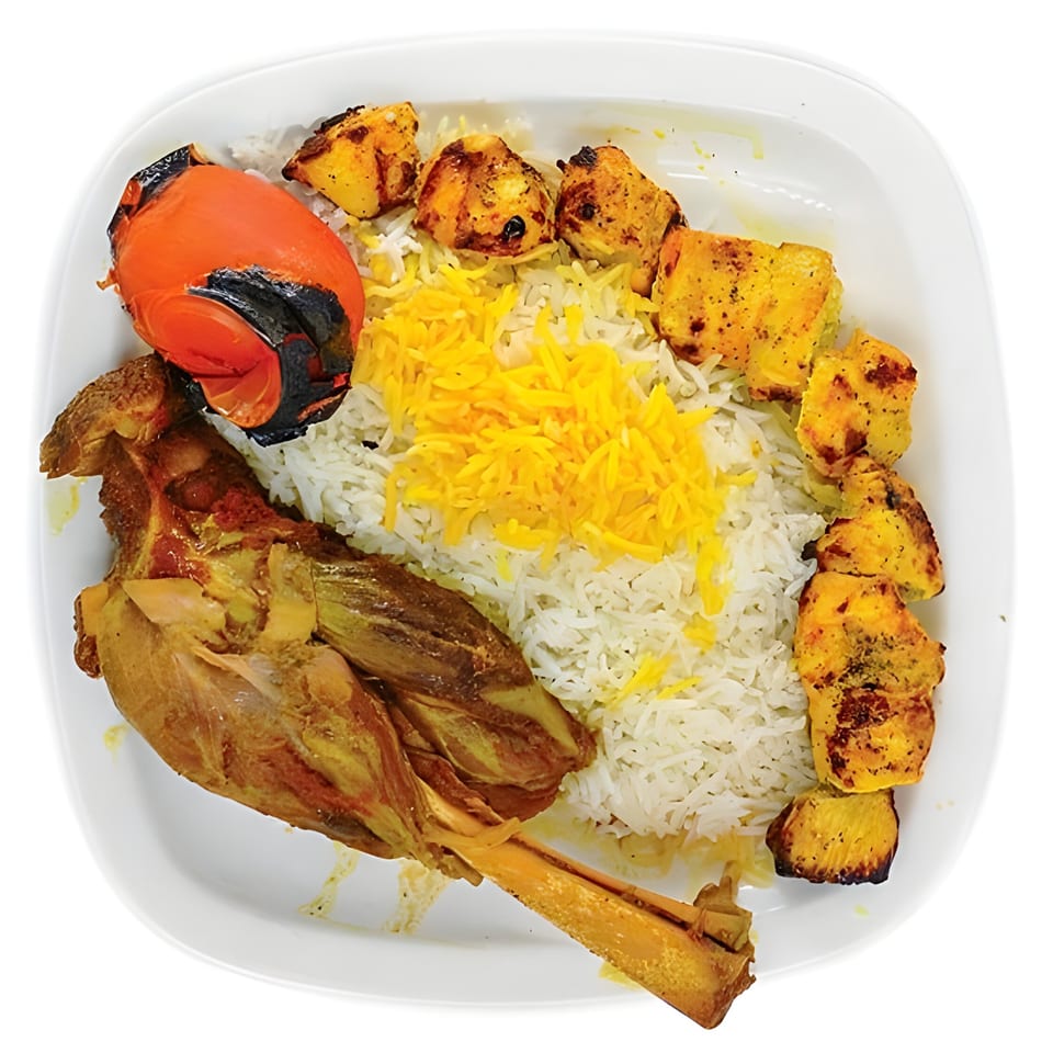 Persian dish with a lamb shank, chicken kabob, grilled tomato, and saffron rice on a white plate.